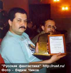 Серьезный Лукьяненко показывает премию и диплом